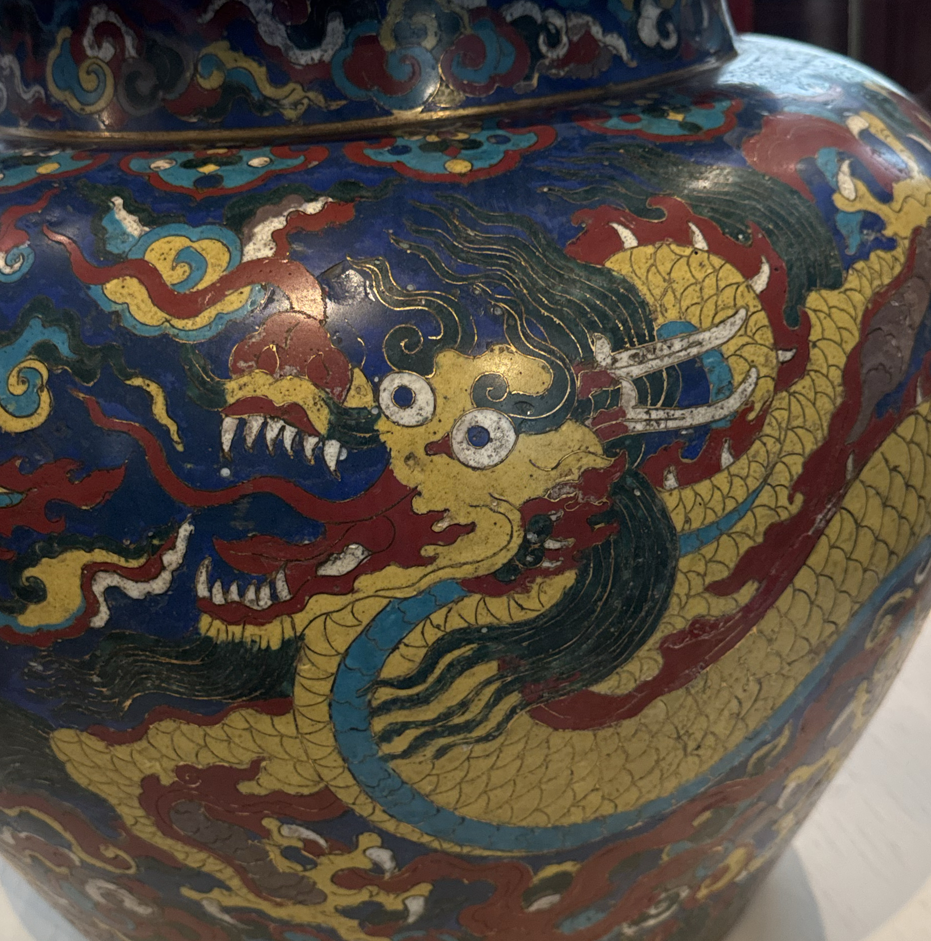 Close-up of a colorful cloisonné vase with a yellow dragon on blue enamel