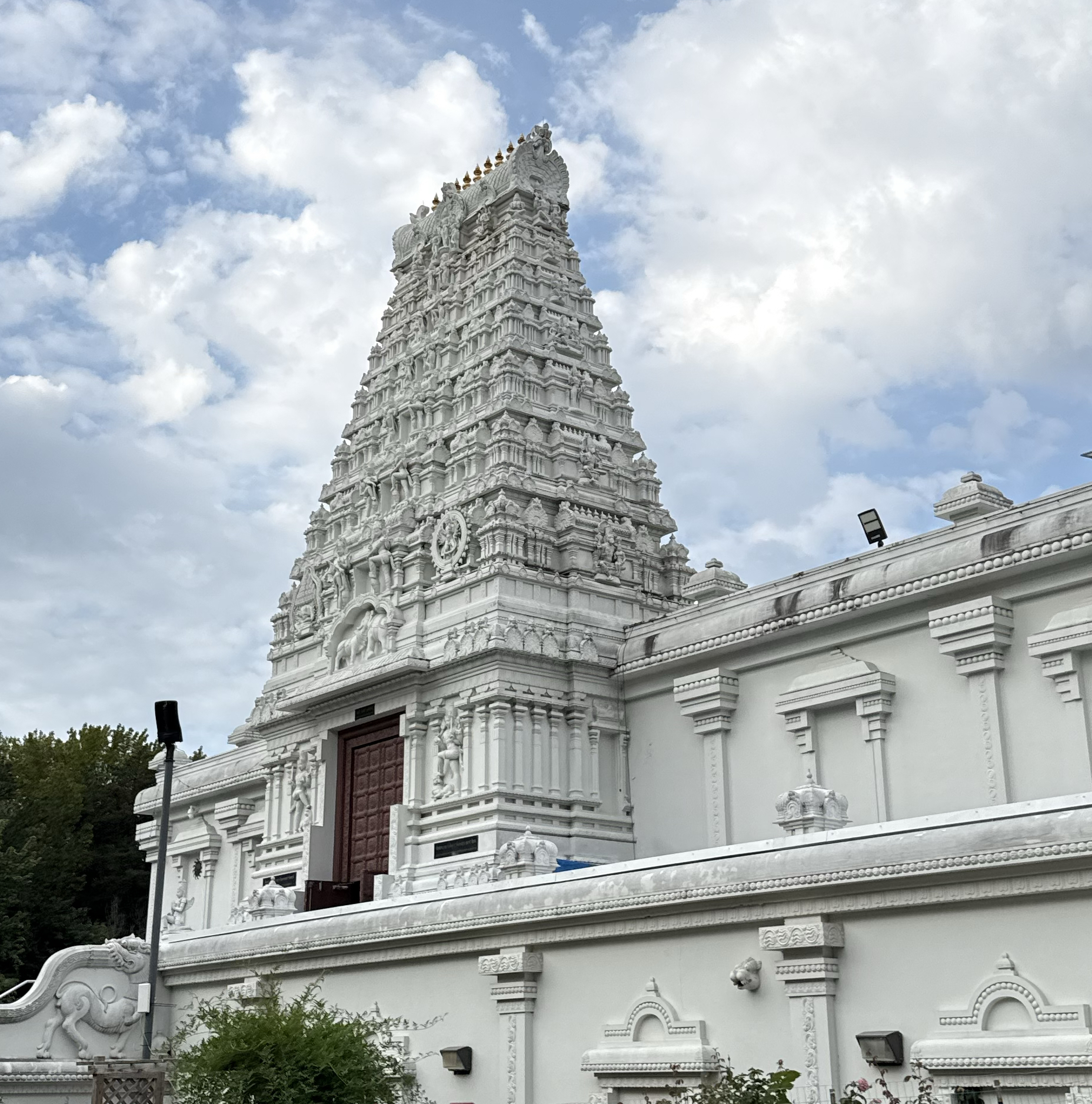 White South Indian-style temple tower (gopuram) against a partly cloudy sky