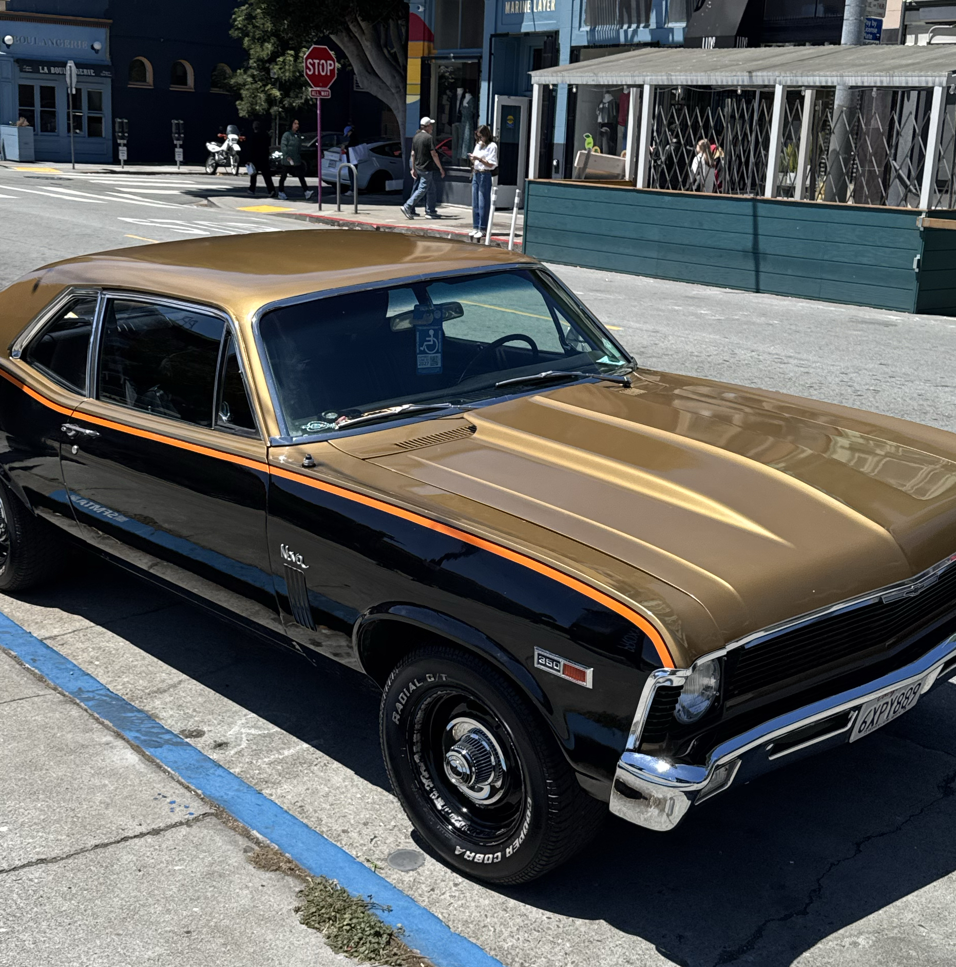 Gold-and-black classic Chevy Nova parked on a city street
